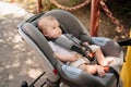 a little boy lies strapped in a stroller-carrier.