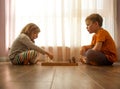 Little boy and little girl are playing chess at home. Children sitting on the floor near window and playing chess Royalty Free Stock Photo