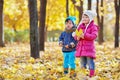 Little boy and little girl stand in autumn park,