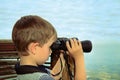 Little boy looking through binoculars at sea. side view, toning Royalty Free Stock Photo