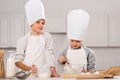 little boy looking at camera and his sister whisking eggs in bowl at table Royalty Free Stock Photo