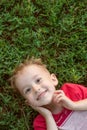 Little boy looking at camera lying on green grass