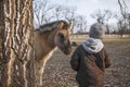 Little boy looking at little foal horse hiding behind the tree, biosphere reserve, wildlife