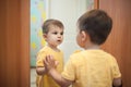 Little boy looking at himself near mirror; Royalty Free Stock Photo