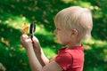 Little boy looking through a magnifying glass on the leaf. Interest in science in children. Curiosity the concept