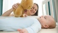 Little boy looking and reaching for teddy bear in his cradle. Concept of parenting, family happiness and baby Royalty Free Stock Photo