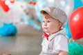 Little boy looking side with mouth covered in white icing and cake in decorated studio backdrop. Birthday cakesmash Royalty Free Stock Photo