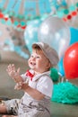 Little boy looking side with mouth covered in white icing and cake in decorated studio backdrop. Birthday cakesmash Royalty Free Stock Photo