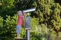 Little boy looking in telescope for tourists on observation deck. Green park background Royalty Free Stock Photo