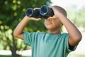 Little boy looking up through binoculars in the park Royalty Free Stock Photo