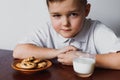 The boy looks with suspicion. Biscuits and milk. Royalty Free Stock Photo