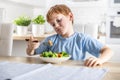 The little boy looks with distaste at the carrot on his fork