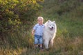 Little boy lovingly embraces white fluffy Samoyed dog. Friendship between man and animal. Traveling Royalty Free Stock Photo