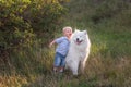 Little boy lovingly embraces white fluffy Samoyed dog. Friendship between man and animal. Traveling Royalty Free Stock Photo