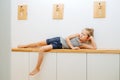 Little boy lying on a corridor shelf, leaning on his hand