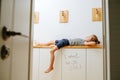 Little boy lying on a corridor shelf trying to kill some time in isolation