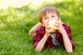 Little boy lying on grass with apple Royalty Free Stock Photo