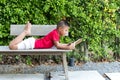Little boy lying on the wooden bench reading a book Royalty Free Stock Photo