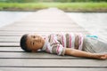 Little boy lying on wooden bridge at park.