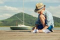 Little boy make paper boats sitting on the wooden pier