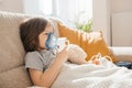 Little boy makes inhalation with a nebulizer at home lying on the couch. Cough prevention and treatment at home