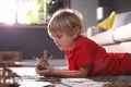 Boy making cardboard toys on floor at home. Creative hobby Royalty Free Stock Photo