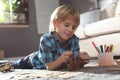 Boy making cardboard toys on floor at home. Creative hobby Royalty Free Stock Photo