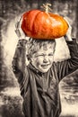 Little boy making a face with heavy orange pumpkin hat