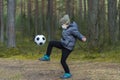 Little boy with a mask due to the corona virus kicking ball in the park. Coronavirus quarantine. Royalty Free Stock Photo