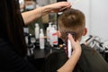 little boy in a mask, which is cut in the barbershop in the barbershop, fashionable and stylish haircut for a child.