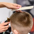 little boy in a mask, which is cut in the barbershop in the barbershop, fashionable and stylish haircut for a child. Royalty Free Stock Photo