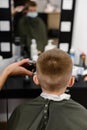 little boy in a mask, which is cut in the barbershop in the barbershop, fashionable and stylish haircut for a child. Royalty Free Stock Photo