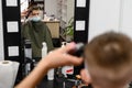 little boy in a mask, which is cut in the barbershop in the barbershop, fashionable and stylish haircut for a child. Royalty Free Stock Photo