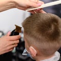 little boy in a mask, which is cut in the barbershop in the barbershop, fashionable and stylish haircut for a child. Royalty Free Stock Photo