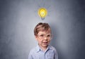 Little boy mull over with bulb above his head Royalty Free Stock Photo