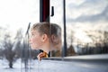 Little boy in orange jacket leaning head out bus window looking up winter sky. Royalty Free Stock Photo