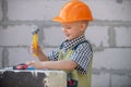 Little boy in orange protective helmet with instruments for renovation. Repair home. Royalty Free Stock Photo