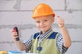 Little boy in orange protective helmet with instruments for renovation. Smiling happy kids builder and repair. Royalty Free Stock Photo