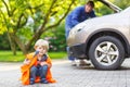 Little boy in orange safety vest during his father repairing family car Royalty Free Stock Photo