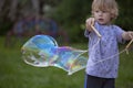 Young, 4 year old preschool boy with a grey shirt and blond hair, blowing bubbles in the yard Royalty Free Stock Photo