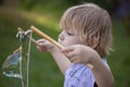 Young, 4 year old preschool boy with a grey shirt and blond hair, blowing bubbles in the yard Royalty Free Stock Photo