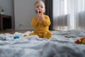 A little boy in overalls sits on the floor and holds a toy in his mouth. Single games. Childhood and safe home concept. Royalty Free Stock Photo