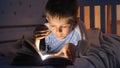 Little boy in pajamas being awake at night reading books with flashlight. Children education, development, secrecy, privacy,