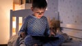 Little boy in pajamas playing video games on tablet computer at night. Children education, development, kids using gadgets secrecy Royalty Free Stock Photo