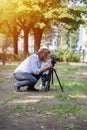 Little boy photographing on the camera on tripod in the park