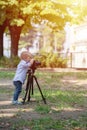 Little boy photographing on the camera on tripod in the park Royalty Free Stock Photo