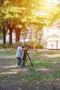 Little boy photographing on the camera on tripod in the park