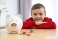 Little boy with piggy bank and money at home Royalty Free Stock Photo