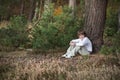 Little boy in a pinewood forest sitting among pine cones