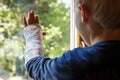 Little boy with a plaster on his arm looking through the window Royalty Free Stock Photo